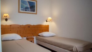 A room with two single beds, wooden headboard, two wall-mounted lamps, and a framed picture on the wall. - 300m from ski slopes, 1st floor, view mountain, swimming pool, sauna, balcony, parking, tv (Le Dévoluy)