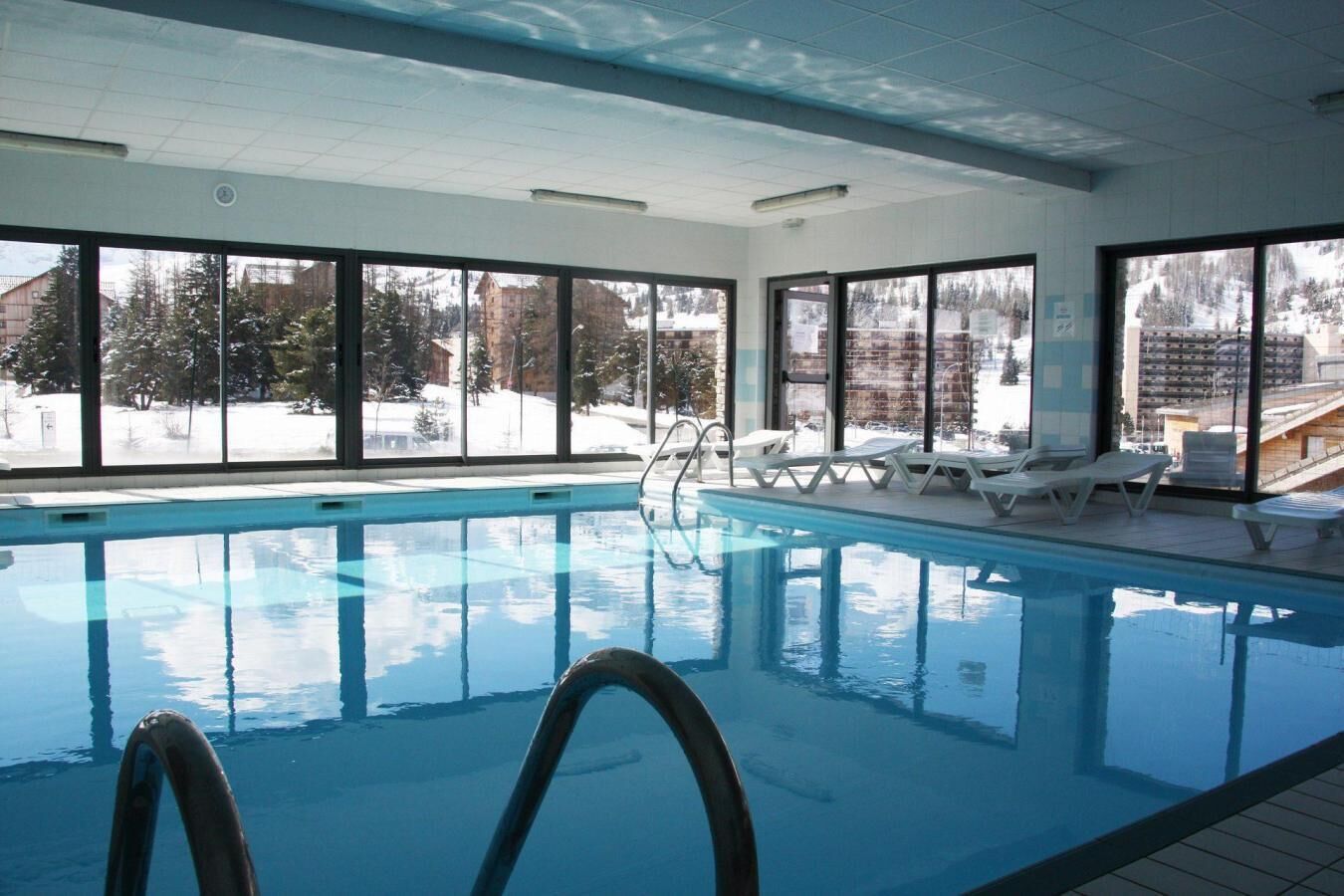 Una piscina interior con vistas despejadas a un paisaje nevado a través de amplias ventanas.