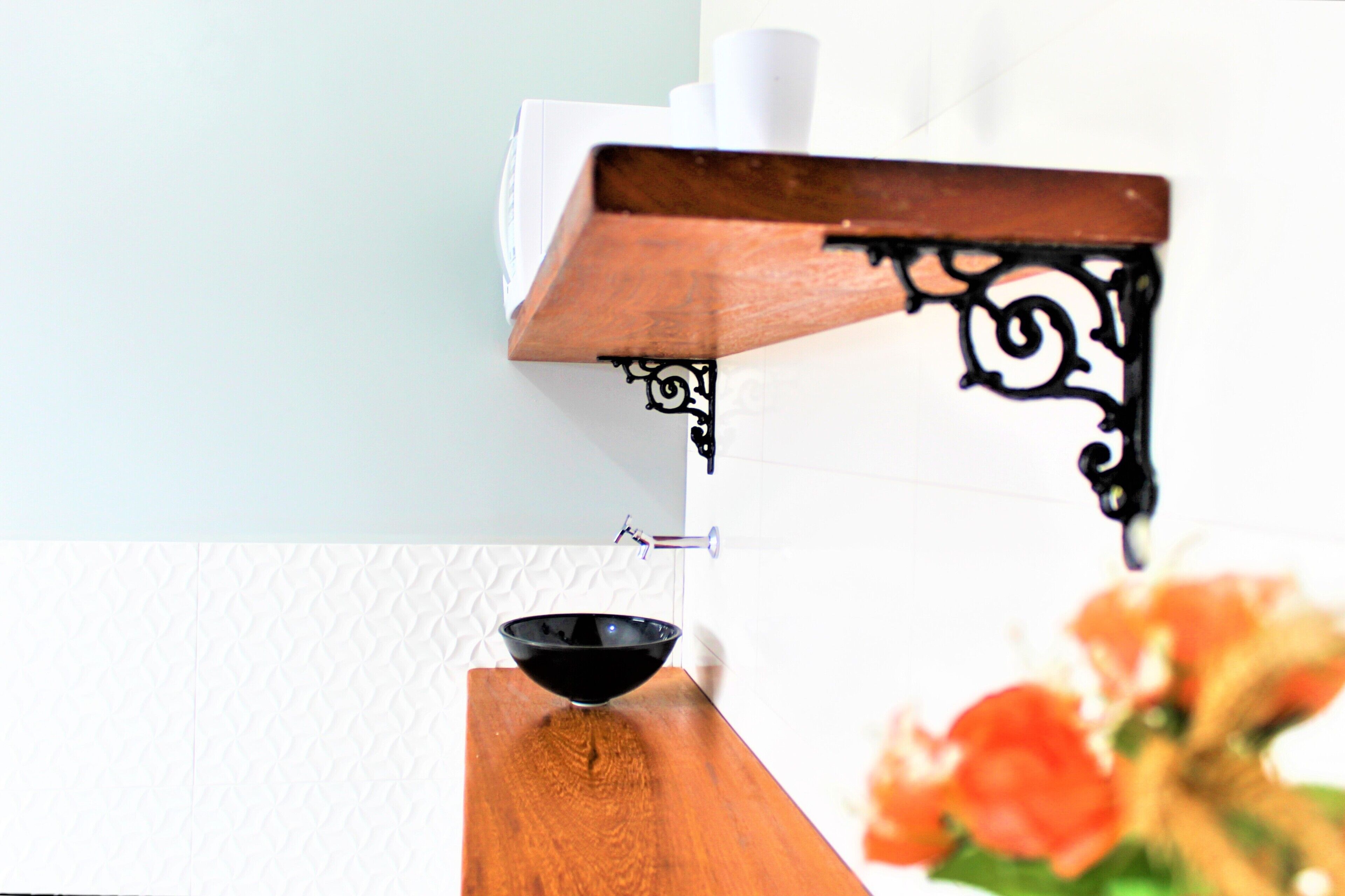 Un baño con tocador de madera, lavabo de cerámica negra y pared blanca con textura.