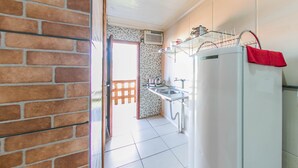 A kitchen with a refrigerator, sink, and an open door leading to a balcony.