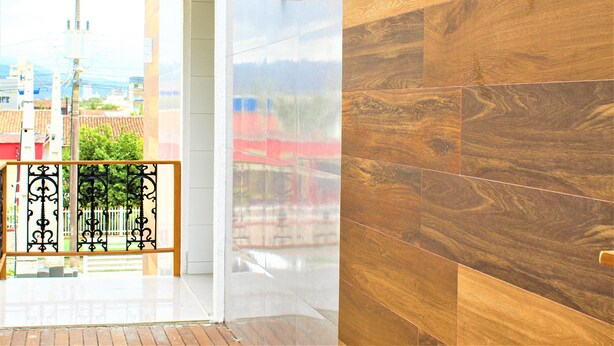 A modern interior with a wooden wall, a glass door leading outside, and a metal railing.