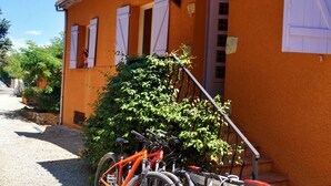 A building with a gravel driveway, a bicycle parked outside, and a staircase leading to the entrance. - Grand F3 - Apartment for 4 to 6 people (Figanières)
