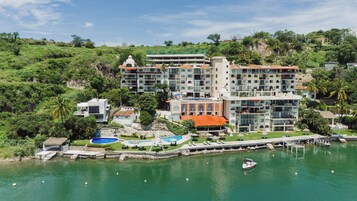 Um hotel com vários edifícios, piscina e um cais com barco.