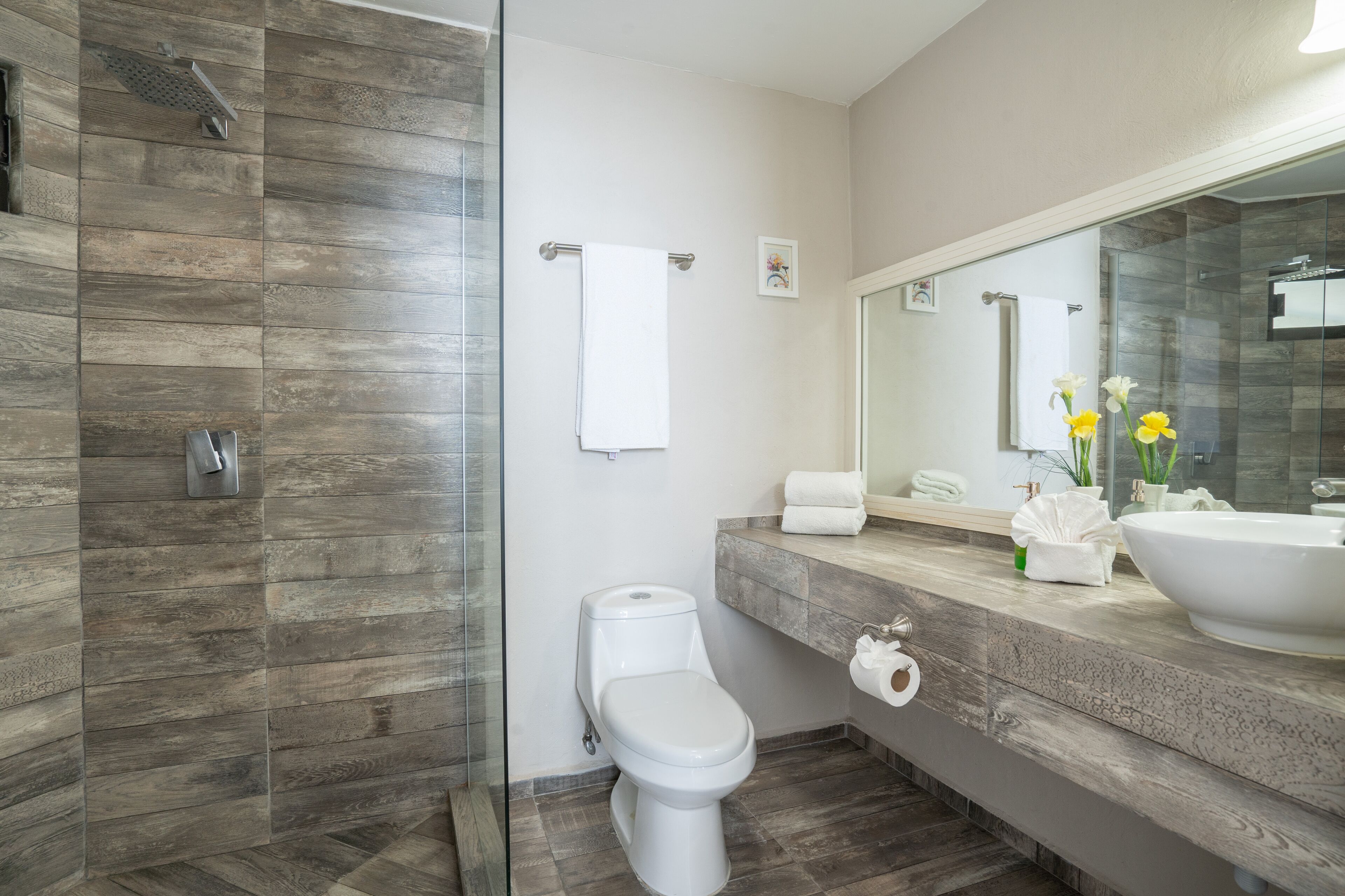 A modern bathroom with a shower, toilet, and vanity.
