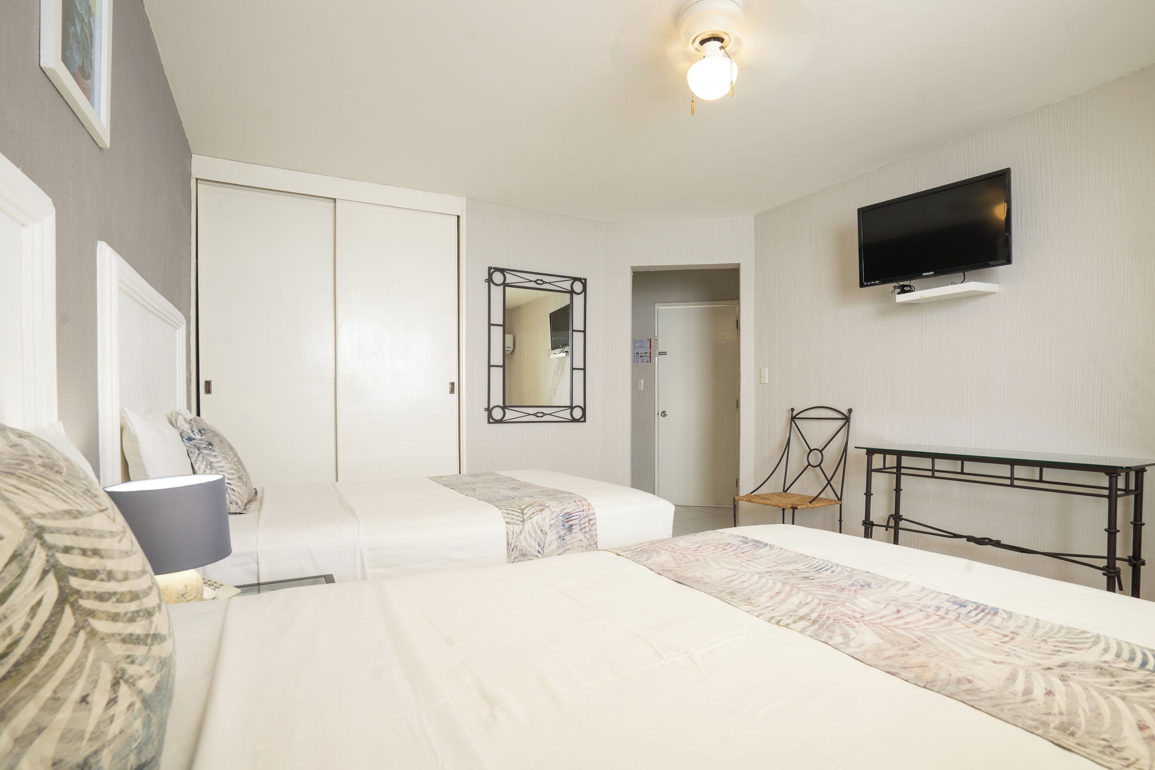 Ett hotellrum med två sängar, en tv, en spegel och ett skrivbord.