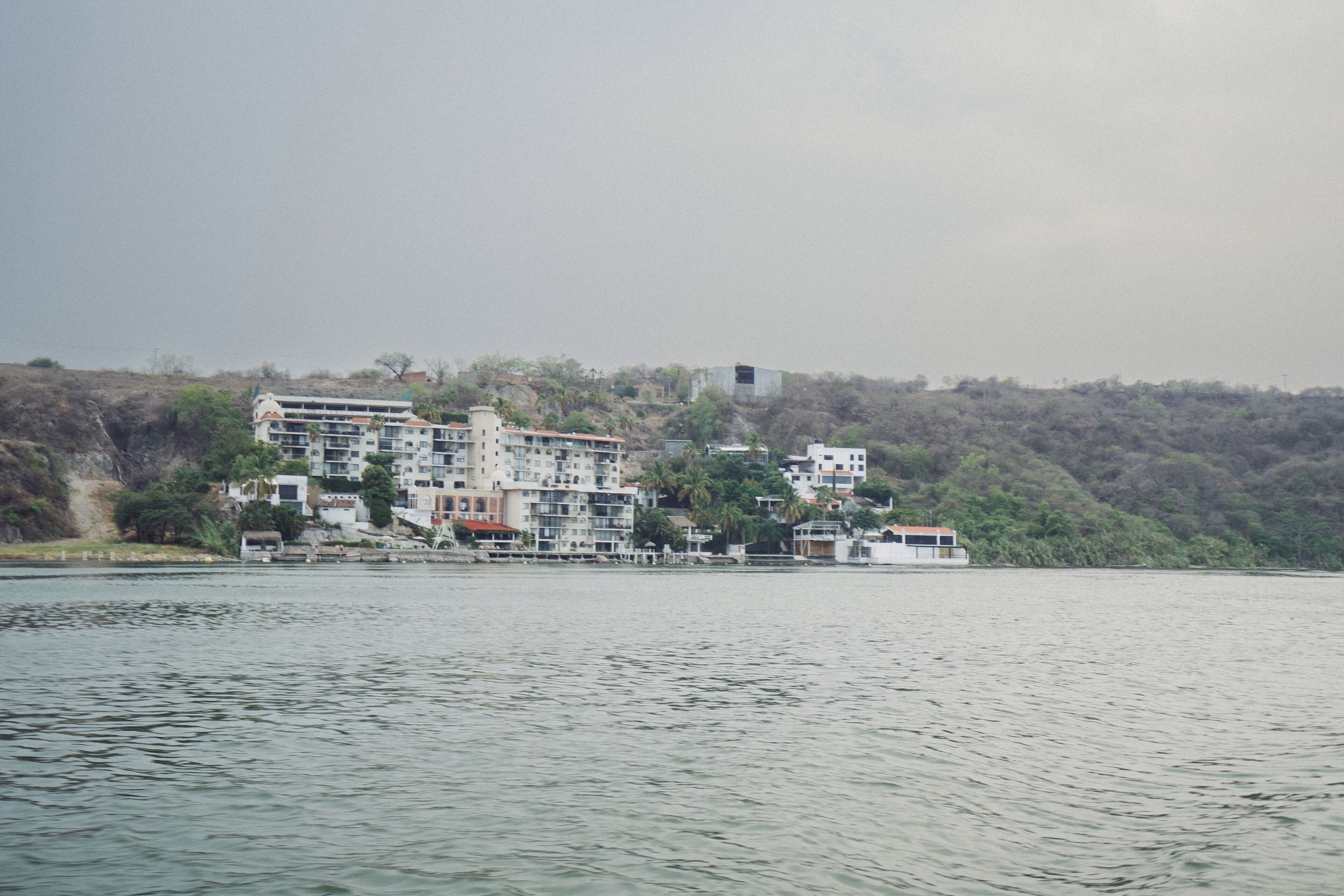 A waterfront hotel with multiple buildings, some with balconies, situated along a river.