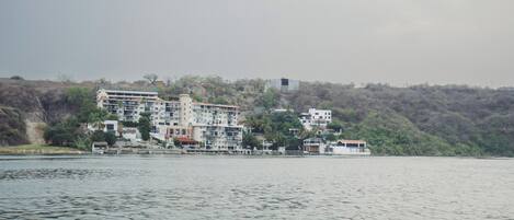 A waterfront hotel with multiple buildings, some with balconies, situated along a river.