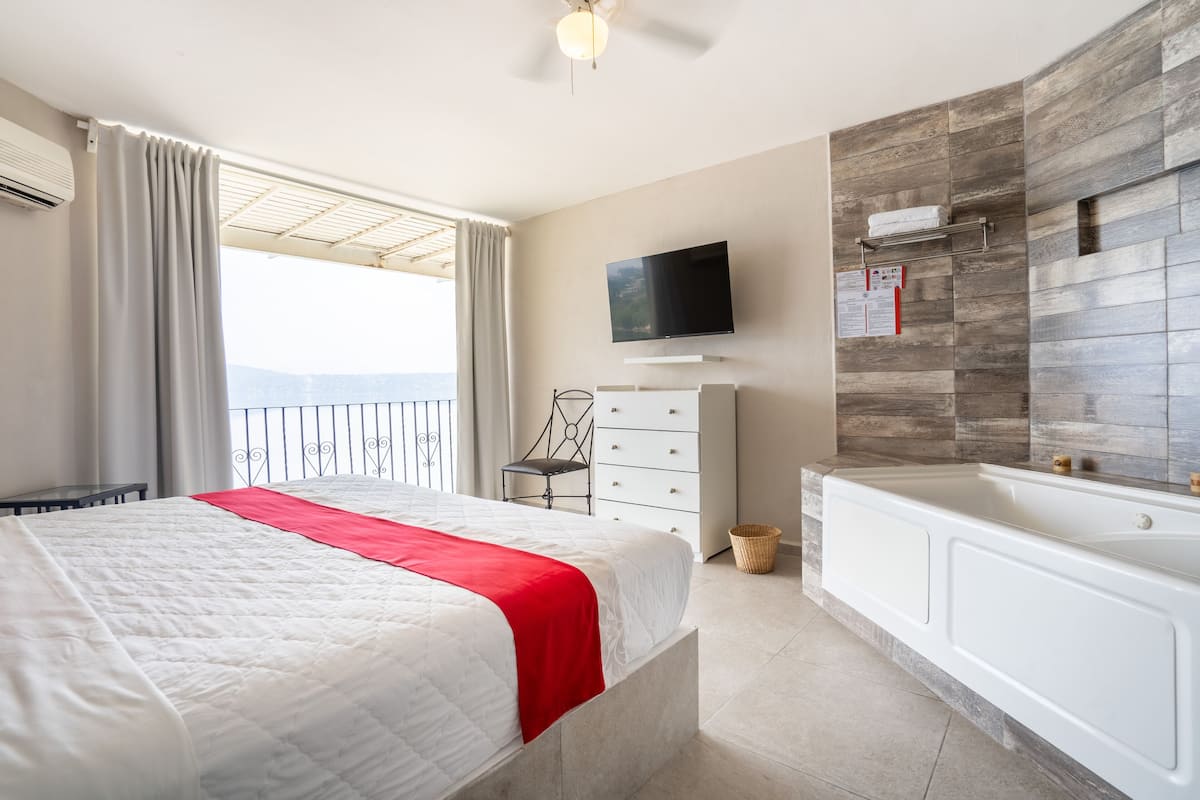 Ein Hotelzimmer mit Bett, Fernseher, Badezimmer mit Badewanne und Blick auf die Berge.