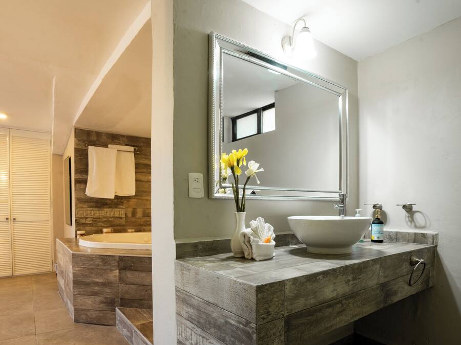 Un baño moderno con un espejo grande, una bañera y un tocador con lavamanos y toallero.