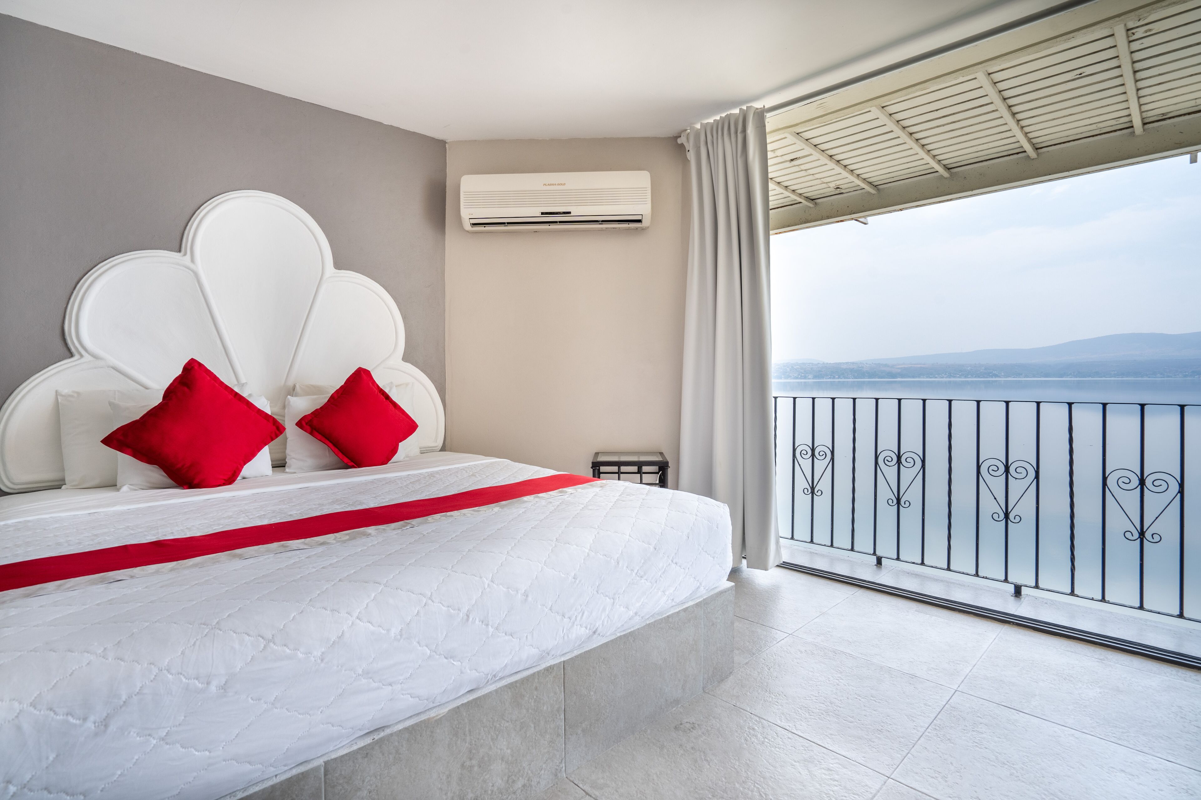 Une chambre moderne avec un grand lit, une vue sur la mer et un climatiseur fixé au mur.
