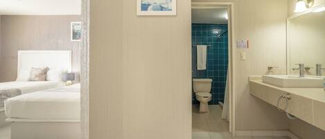 Una habitación de hotel con cama, baño con lavamanos y ducha.