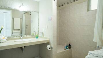 A bathroom with a sink, mirror, towel rack, shower, and toiletries.