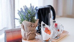 Ein Tisch mit einer mit Jute umwickelten Pflanze, drei Gläsern mit Teebeuteln und einer schwarzen Tasche.