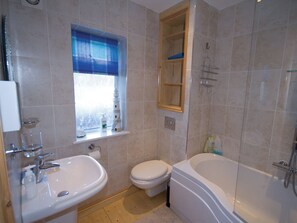 A bathroom with a sink, toilet, bathtub, and a window with a blue curtain. - 3 bedroom accommodation in Whitby (Whitby)