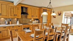 A kitchen with wooden cabinets, a dining table set for six, and a chandelier. - 3 bedroom accommodation in Whitby (Whitby)