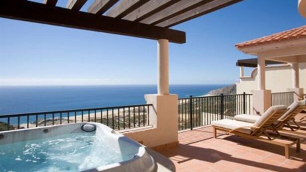 Un jacuzzi en un balcón con vista al océano.