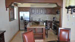 Una cocina con armarios de madera oscura, encimera de granito, electrodomésticos de acero inoxidable y un comedor con mesa y sillas.