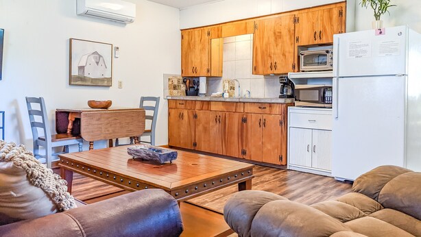 Eine kleine Küche mit Holzschränken, einem weißen Kühlschrank und einer Mikrowelle.