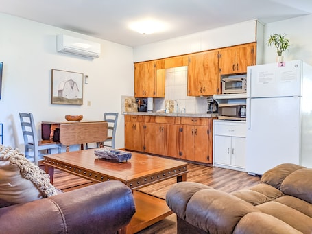 A compact kitchen with wooden cabinets, a white refrigerator, and a microwave.