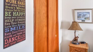 Ein motivierender Wandspruch, eine Holztür, eine Lampe und ein gerahmtes Bild auf einem Tisch.
