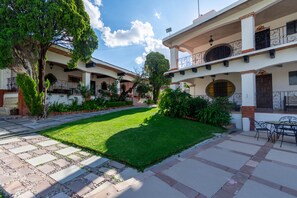 A courtyard with a well-maintained lawn, stone pathway, and outdoor seating area. - Hotel Parador del Cortijo Spa (San Miguel de Allende)