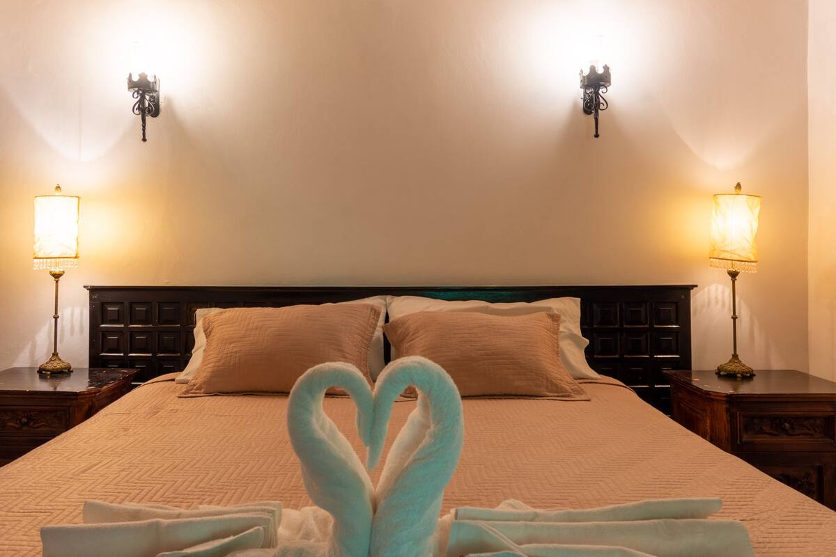Una camera d'albergo con un letto, due comodini e due lampade a parete.