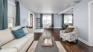 A spacious living room with a sofa, armchair, and a coffee table. - Cozy Downtown Greenwood Retreat - Walkable to Everything (Greenwood)