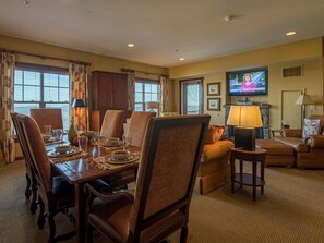 A hotel room with a dining area, a living room with a sofa and armchairs, a television, and a fireplace. - 3 Br: Soaring Eagle 301 (Snowshoe)