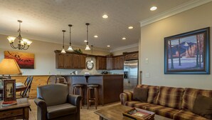 A living room with a sofa, armchair, coffee table, and a dining area with chairs and a lamp. - 5 Br: Black Bear Crossing #4 (Snowshoe)
