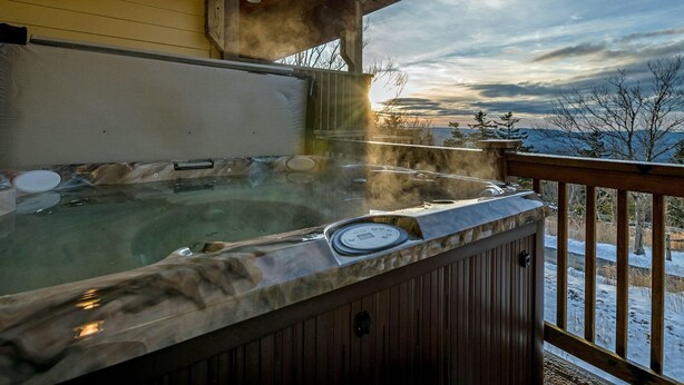 A hot tub on a wooden deck with a view of a snowy landscape and mountains in the background. - 5 Br: Black Bear Crossing #4 (Snowshoe)
