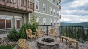 Un patio con mobiliario exterior, una fogata y vistas a una cadena montañosa.