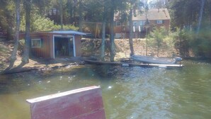 A cabin with a dock and a small shed by a lake surrounded by trees. - Family friendly lakefront cottage (Pickerel)
