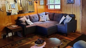 A cozy living room with a sectional sofa, a coffee table, and a small side table. - Family friendly lakefront cottage (Pickerel)