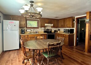 A kitchen with wooden cabinets, a central island, and a chandelier. - Cozy Cottage (Pickerel)