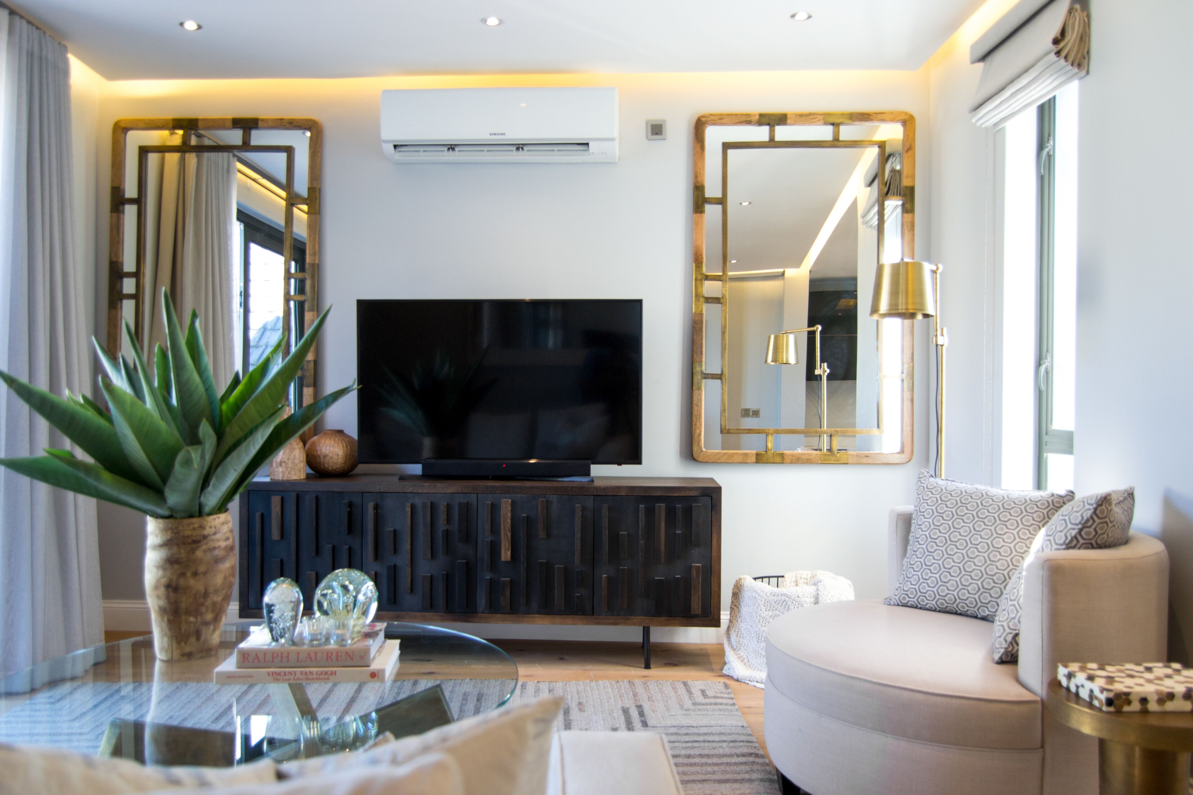 A modern living room with a flat-screen TV, a sofa, a coffee table, and decorative items.
