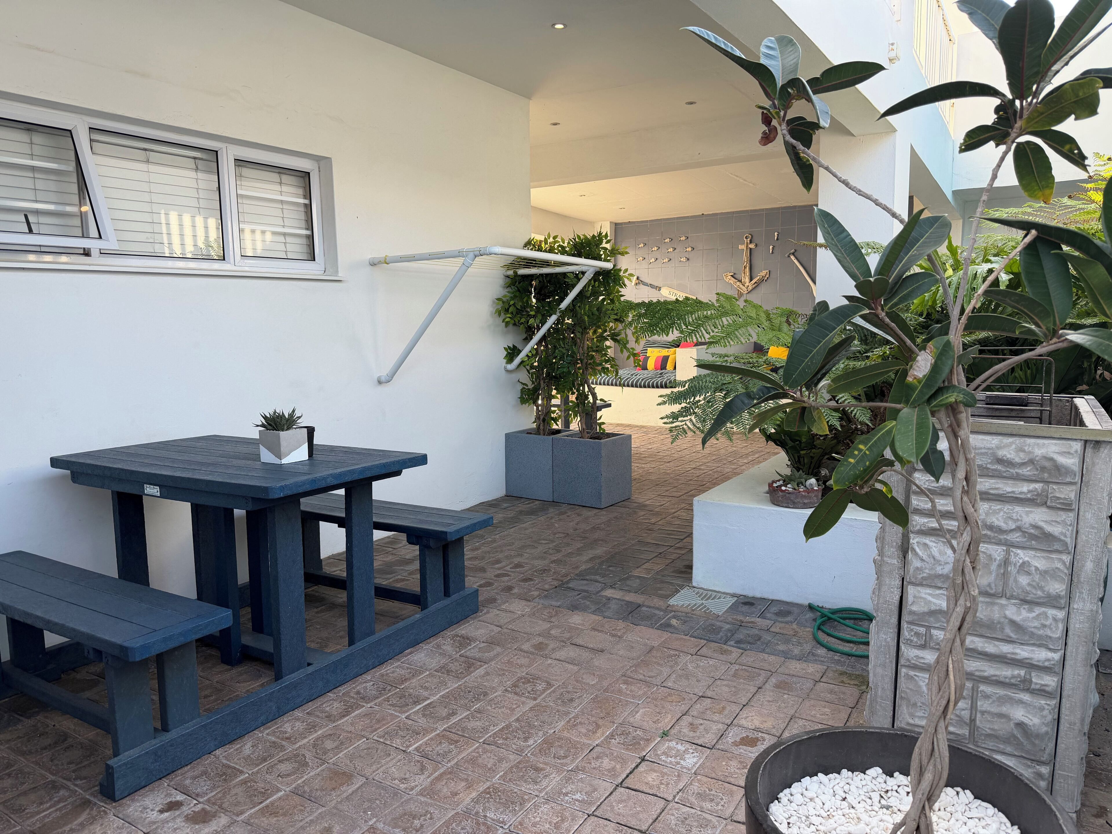 A patio area with a table and benches, potted plants, and a stone wall.