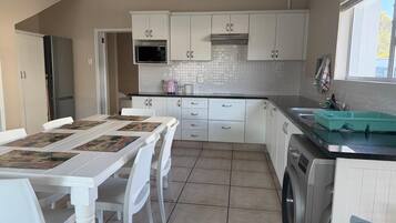 A kitchen with white cabinets, a washing machine, and a dining area with a table and chairs.