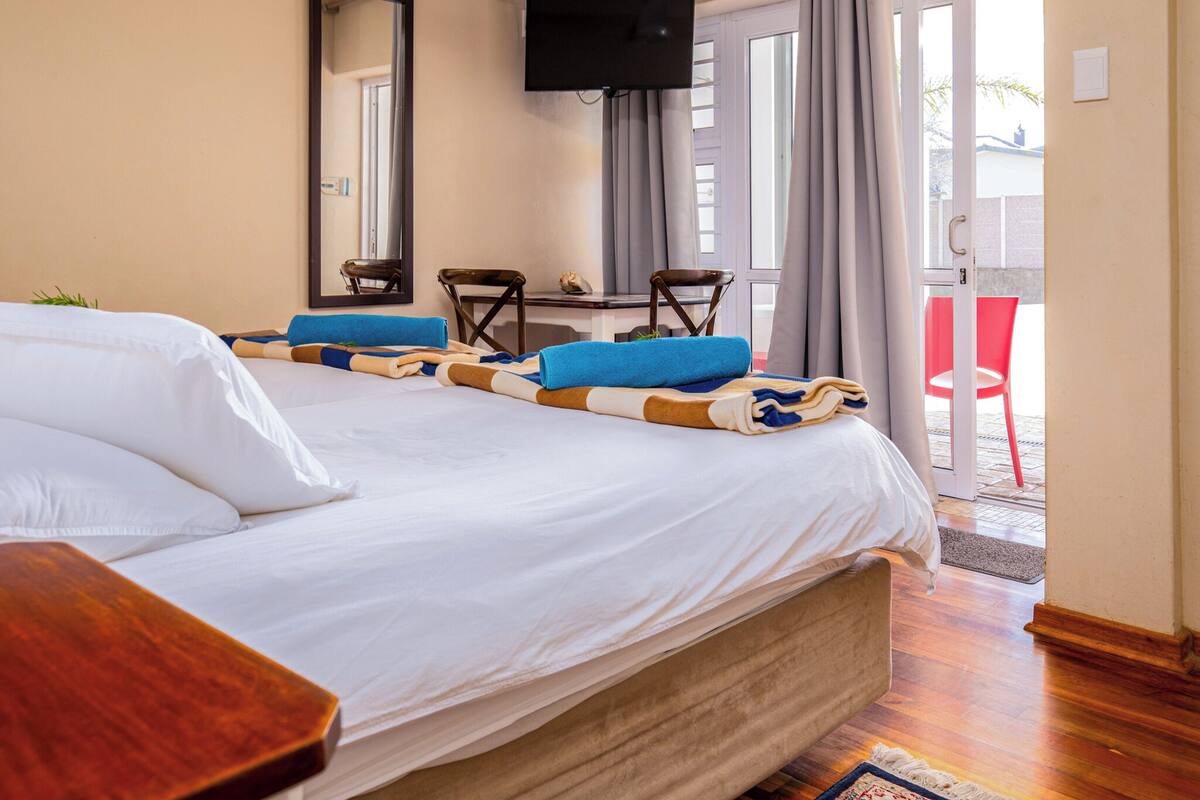 A hotel room with a bed, a desk, a chair, a television, and a view of the outside.