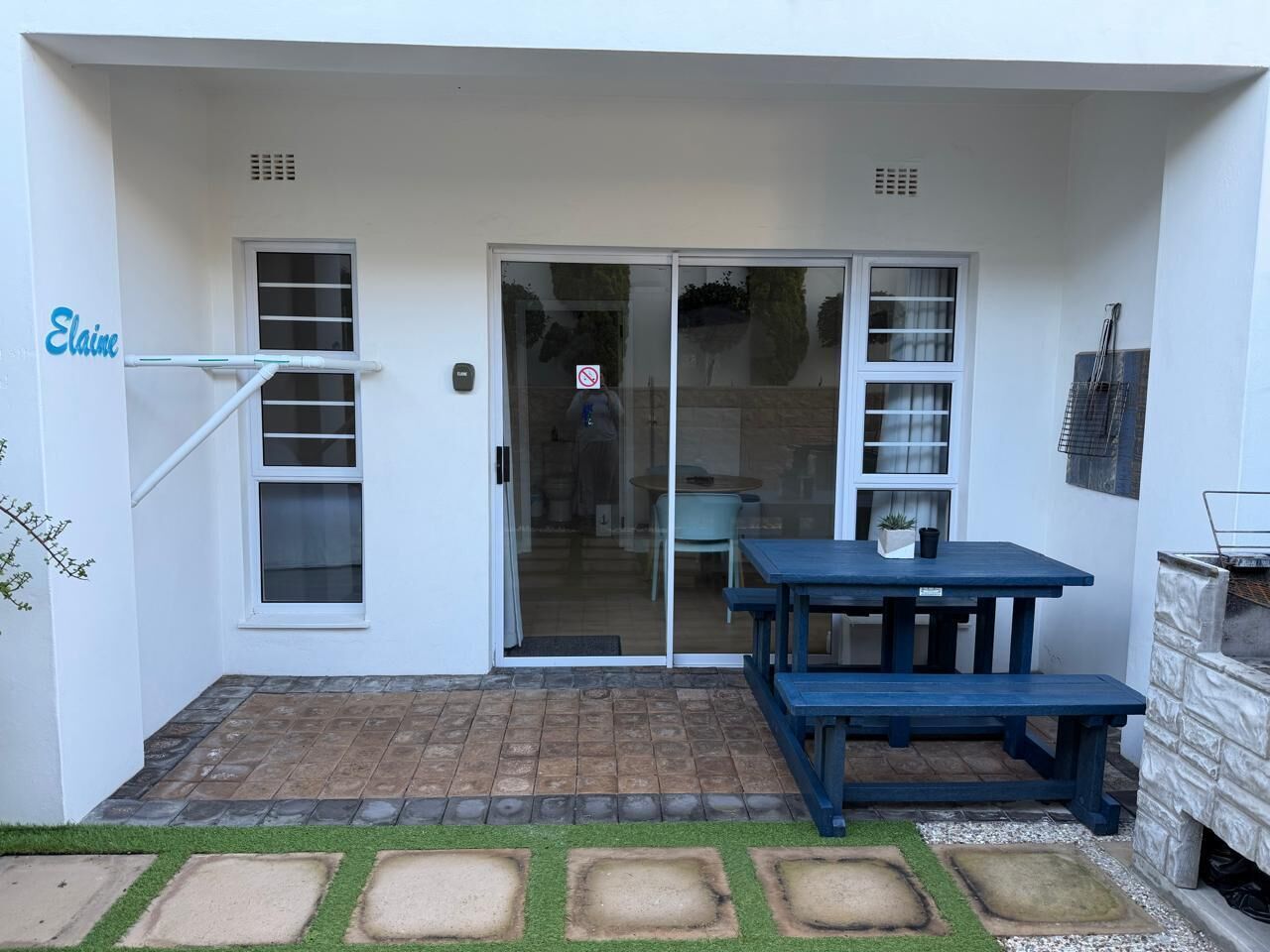 A patio area with a sliding glass door, a blue table, and a stone pathway.