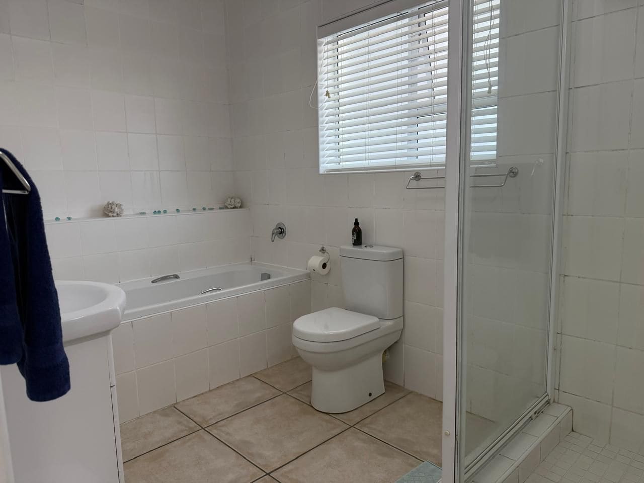 A bathroom with a bathtub, toilet, and a glass-enclosed shower area.