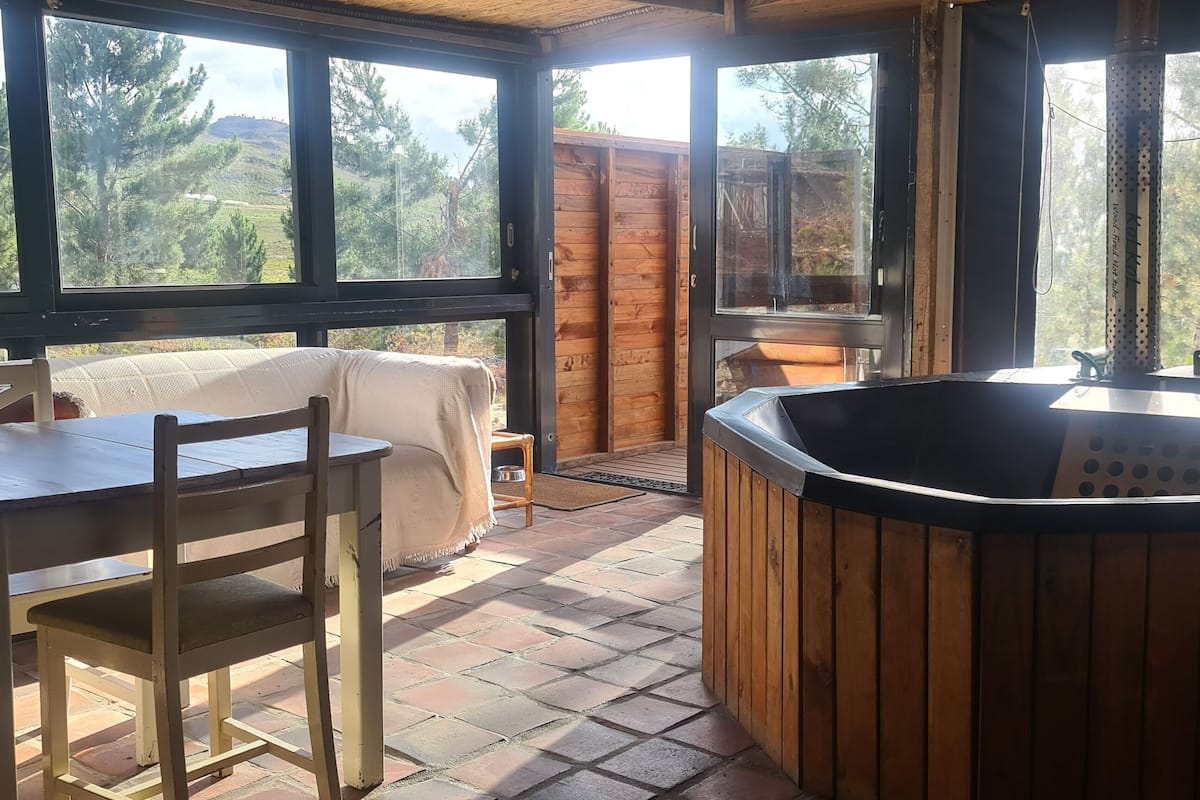 A wooden deck with a hot tub, a table, and chairs.