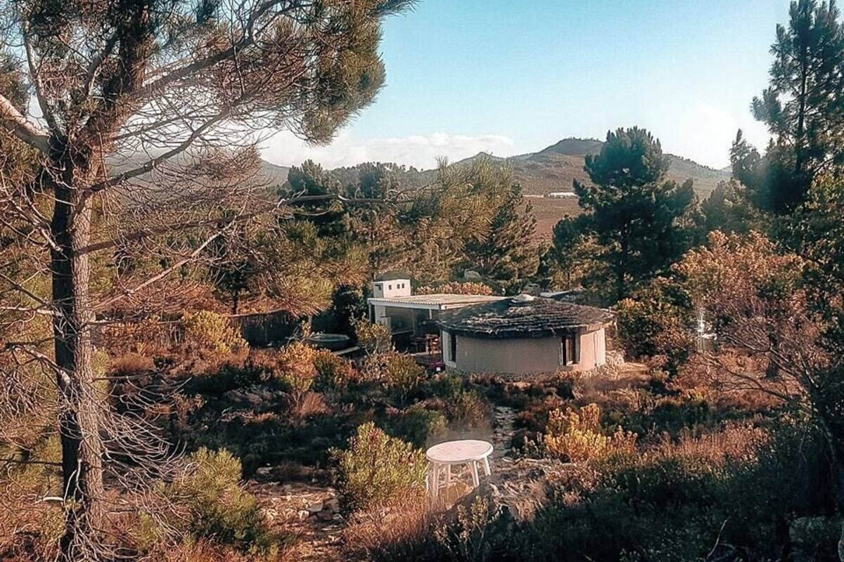 A rustic cabin surrounded by dense forest and hills.