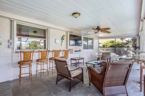 Relax in this serene outdoor space with a ceiling fan, comfortable wicker chairs, and a table.
