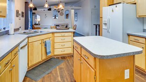A modern kitchen with wooden cabinets, granite countertops, and pendant lighting. - Sea Break - Ocean view with Hot tub (Yachats)