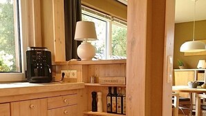 A wooden kitchen with a window, a coffee maker, a lamp, and shelves with jars. - Holiday house complex Hilkenberg house 2, in the middle of nature - romantic and quiet (Bodenfelde)