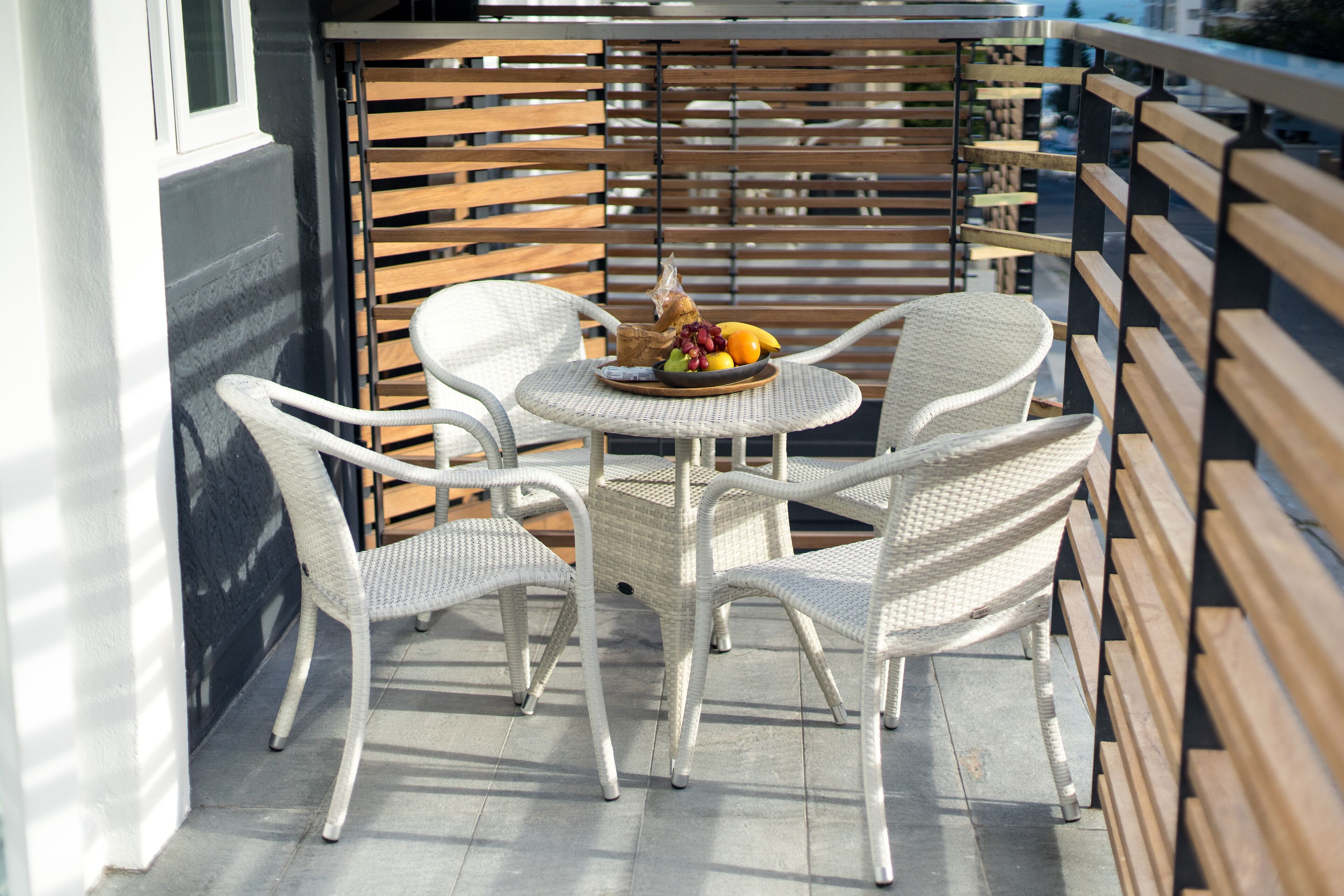 A small outdoor seating area with wicker chairs and a round table, featuring a fruit bowl on the table.