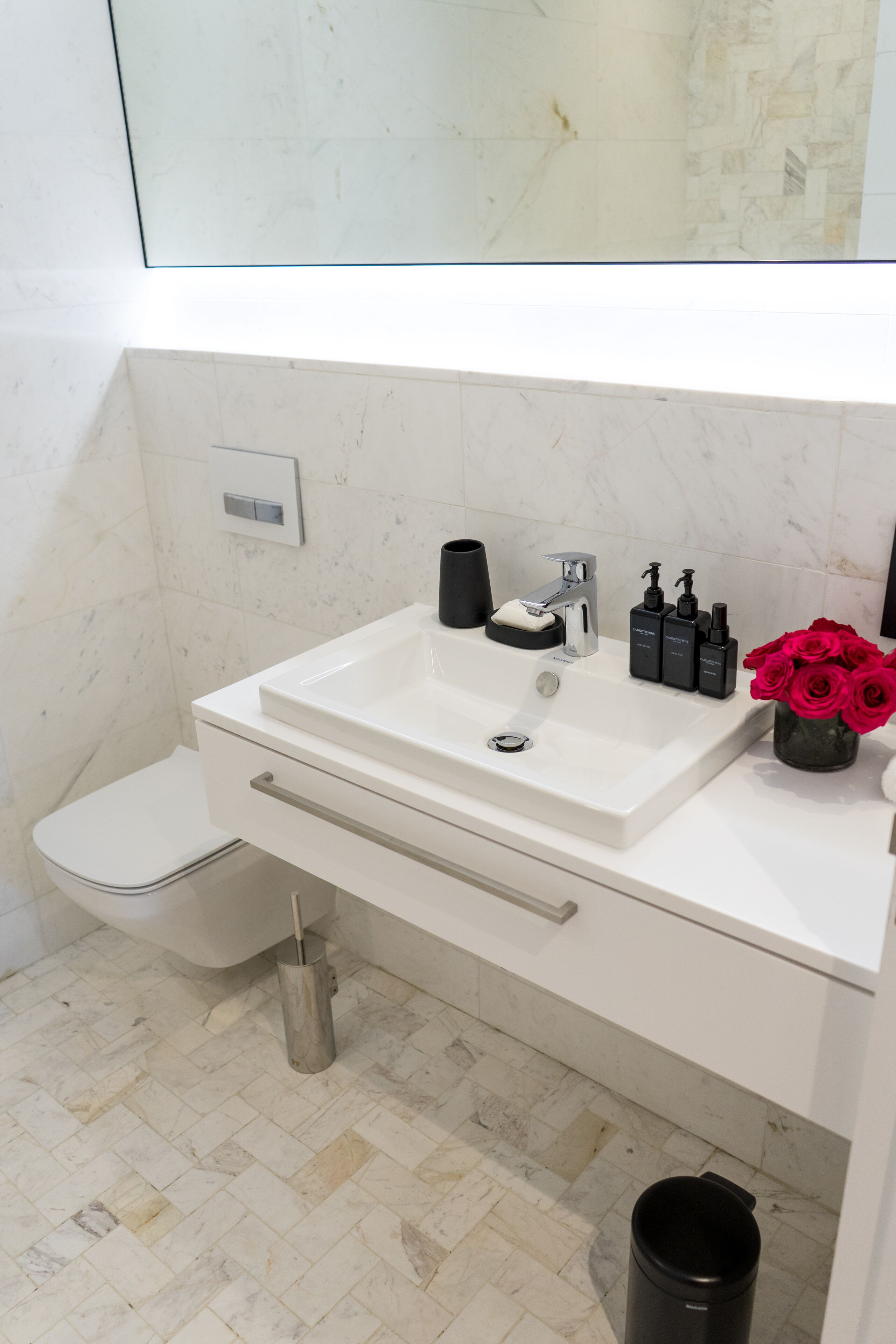Een badkamer met een wit wastafel, toilet en een prullenbak.