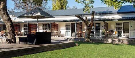A modern building with a covered patio area, outdoor seating, and a well-maintained lawn.