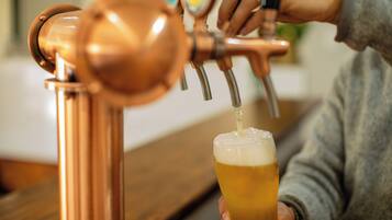 Una persona sirviendo cerveza desde un grifo de cobre en un vaso.