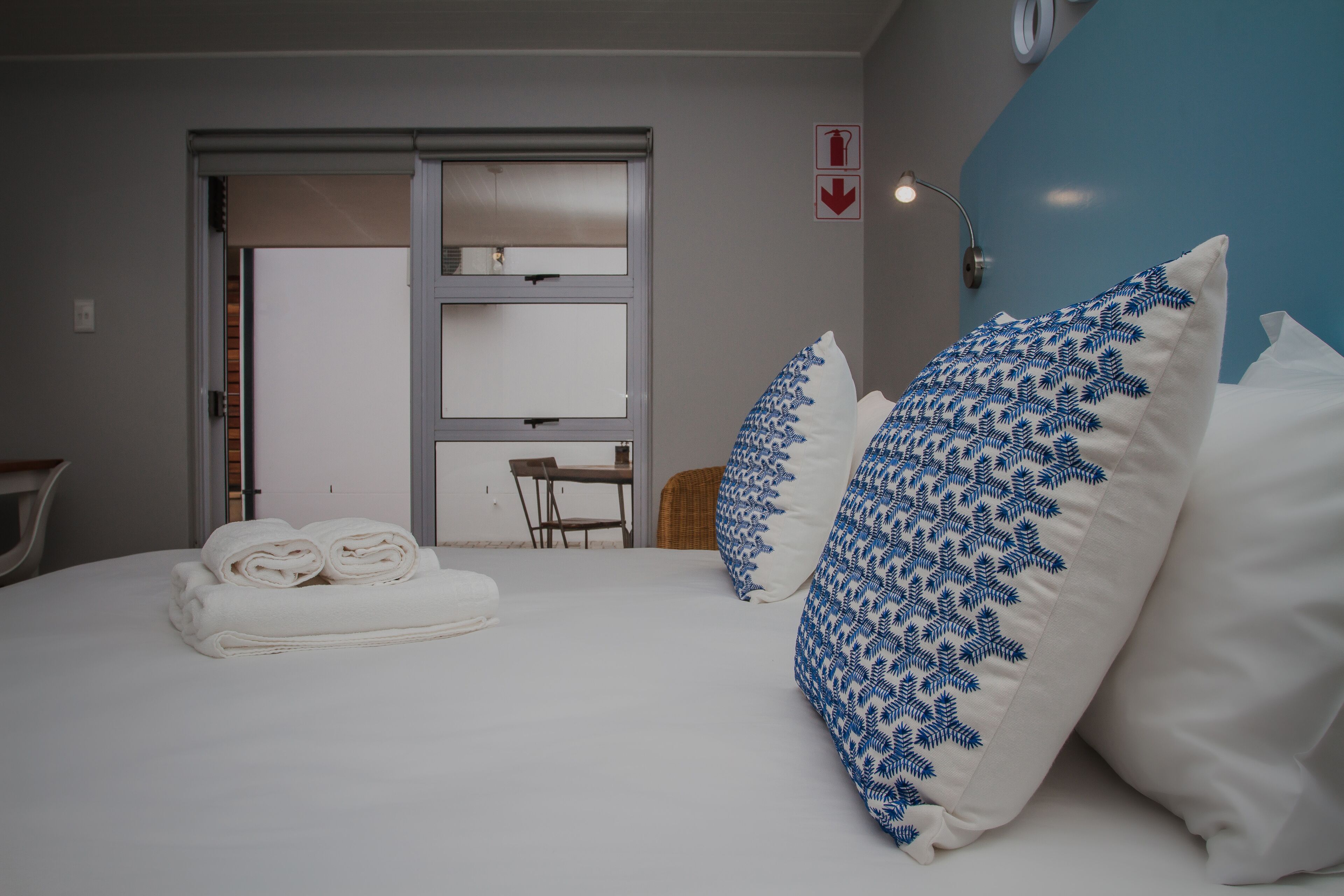A hotel room with a bed, two pillows, a chair, and a table.